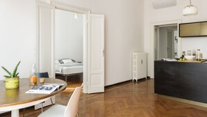 A modern kitchen with a black countertop, white cabinets, and a dining area with a wooden table and chairs. - Macchi Master Guest apartment (Milan)