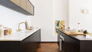 A modern kitchen with dark cabinetry, a white countertop, and a herringbone wood floor. - Macchi Master Guest apartment (Milan)