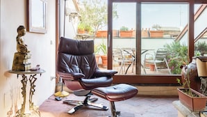 A room with a leather chair, a statue, a framed picture, and a view of the outside. - Morgagni Master Guest apartment (Milan)