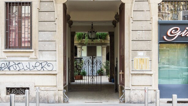 An entrance with a wrought iron gate, a small balcony with plants, and a building facade with a sign. - Morgagni Master Guest apartment (Milan)
