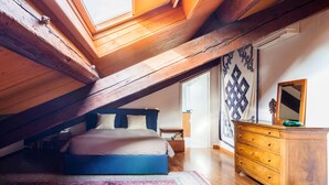 A bedroom with a sloped ceiling, a bed, a dresser, and a patterned wall. - Morgagni Master Guest apartment (Milan)