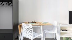 A dining area with a wooden table, two white chairs, and a television on a white shelf. - Anfossi Master Guest apartment (Milan)