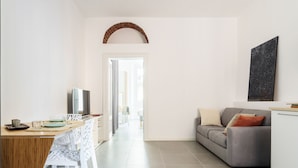 A modern kitchen with a dining area, a grey sofa, and a TV. - Anfossi Master Guest apartment (Milan)