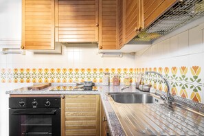 A kitchen with wooden cabinets, a stainless steel sink, and a patterned backsplash. - Orobie Master Guest apartment (Aprica)