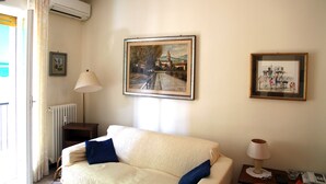 Ein Zimmer mit einem Bett, einer Lampe und zwei gerahmten Bildern an der Wand.