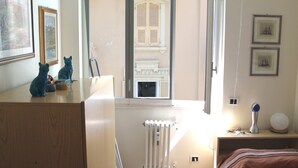 Ein Schlafzimmer mit Holztisch, zwei Betten, einer Heizung und einem Fenster mit Rollläden.