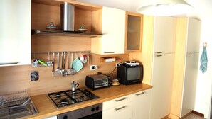 Eine kleine Küche mit Gasherd, Toaster, kleinem Fernseher und Holzschränken.