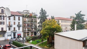 A residential area with multi-story buildings, a street with parked cars, and a tree with yellow leaves. - Asso Master Guest apartment (Milan)
