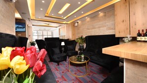 Un espace détente moderne avec des canapés noirs, une table en bois et un tapis à motifs.