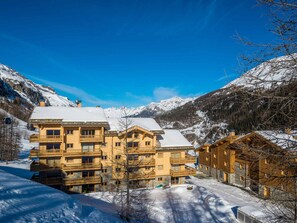 Ein mehrstöckiges Holzhaus mit Balkonen, umgeben von schneebedeckten Bergen.