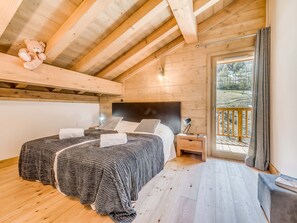 Ein gemütliches Schlafzimmer in einer Holzhütte mit zwei Betten, einem Nachttisch und Blick ins Freie.