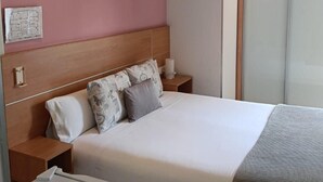 Ein Hotelzimmer mit Bett, Nachttischen, einer Klimaanlage, einem Fenster und einer Wandleuchte.