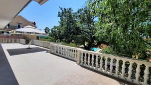A covered outdoor area with a tiled floor, a white railing, and a building with a sign that reads "PAN PAN." - NEW Apartment, A2+2, Family house - OPG Rudan, garden pool, terase, wi-fi (Drnis)