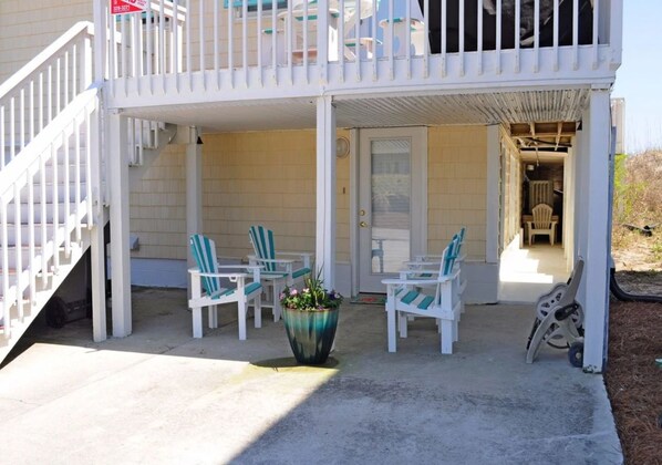 A two-story building with a covered porch, outdoor seating area, and a staircase.