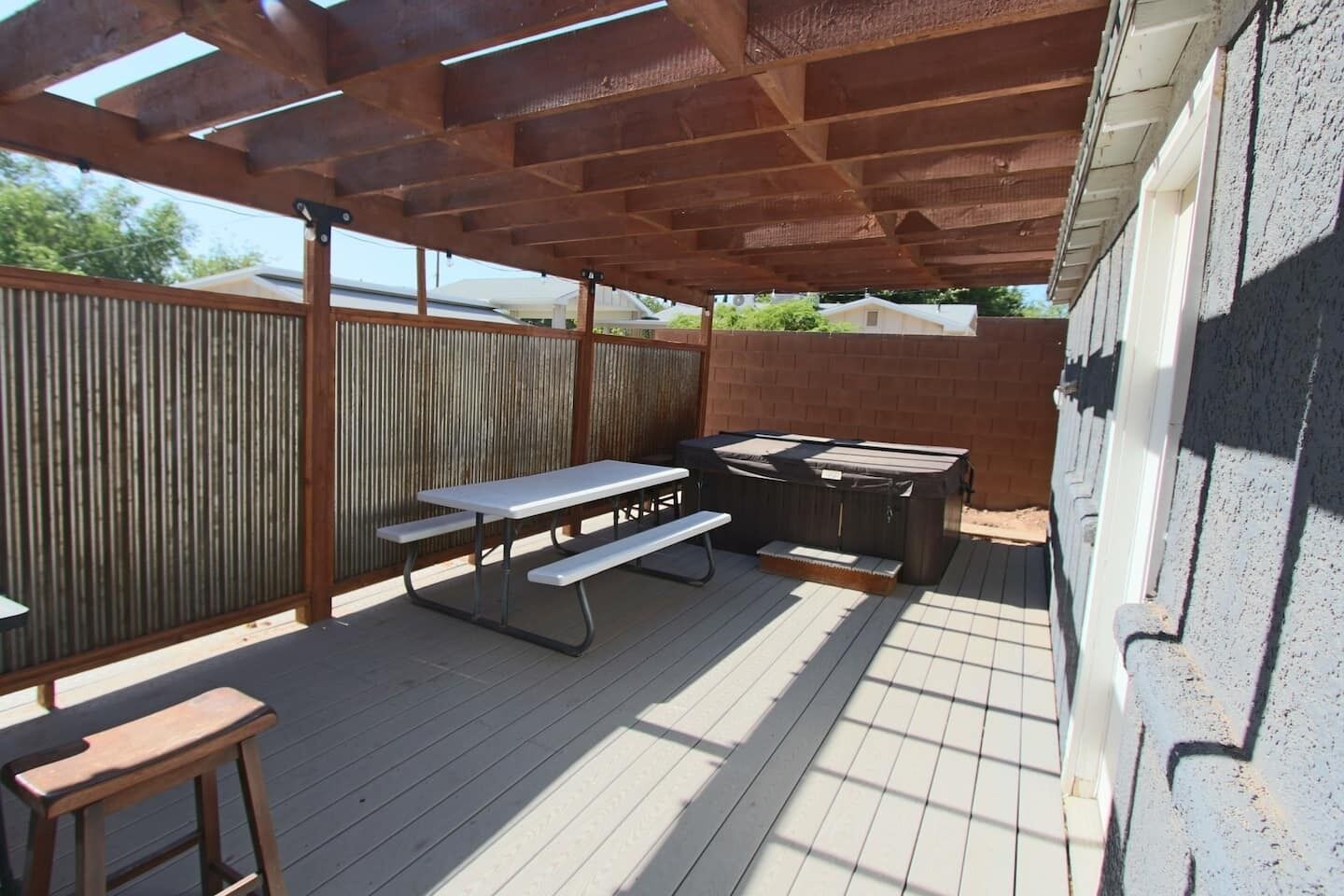 An outdoor patio with a picnic table, a bench, and a hot tub.