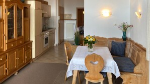 Een gezellige eethoek met houten meubels, een gedekte tafel voor twee en uitzicht op de keuken.