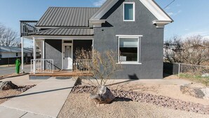 A modern two-story house with a grey exterior, a metal roof, and a small porch with a white railing. - This house is a 11 bedroom(s), 8 bathrooms, located in Hurricane, UT. (Hurricane)