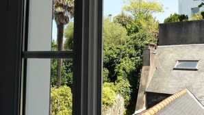 A view from a window overlooking a residential area with a sloped roof and a small skylight. - Bright and quiet apartment 61 m2 5 minutes walk from the Port (Le Palais)