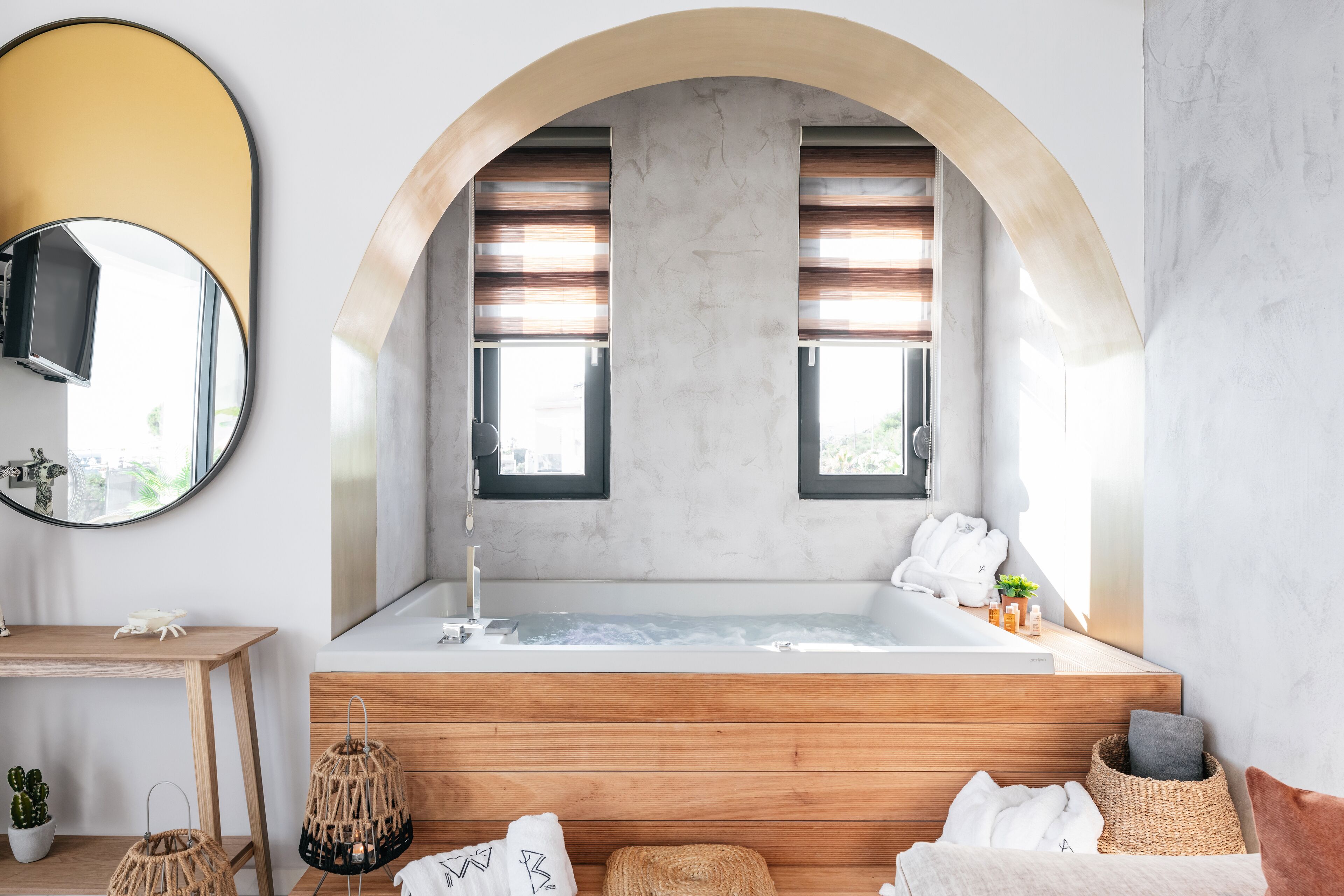 Un bagno moderno con una vasca freestanding, un mobile contenitore in legno e un grande specchio.