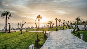 Un sendero empedrado con palmeras y vista al mar al atardecer.