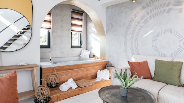 Un baño moderno con una bañera independiente, escalones de madera, un espejo y un diseño circular grande en la pared.