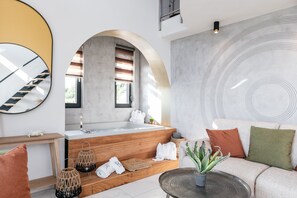 Un baño moderno con una bañera independiente, escalones de madera, un espejo y un diseño circular grande en la pared.