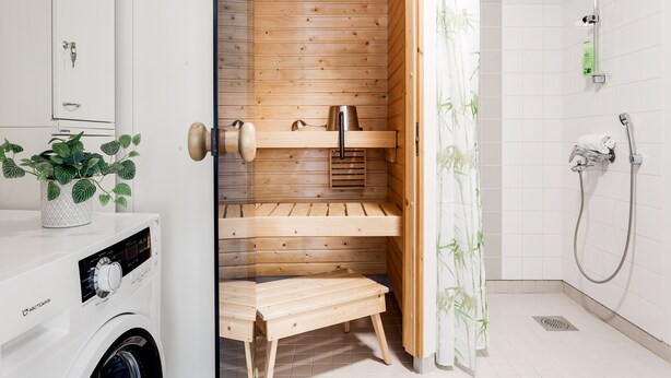 Un baño moderno con sauna de madera, lavadora y zona de ducha.