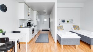 Un espacio habitable moderno y funcional con kitchenette, comedor y dos camas individuales.