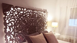 Una cama con un cabecero decorativo, dos almohadas y una lámpara de noche.