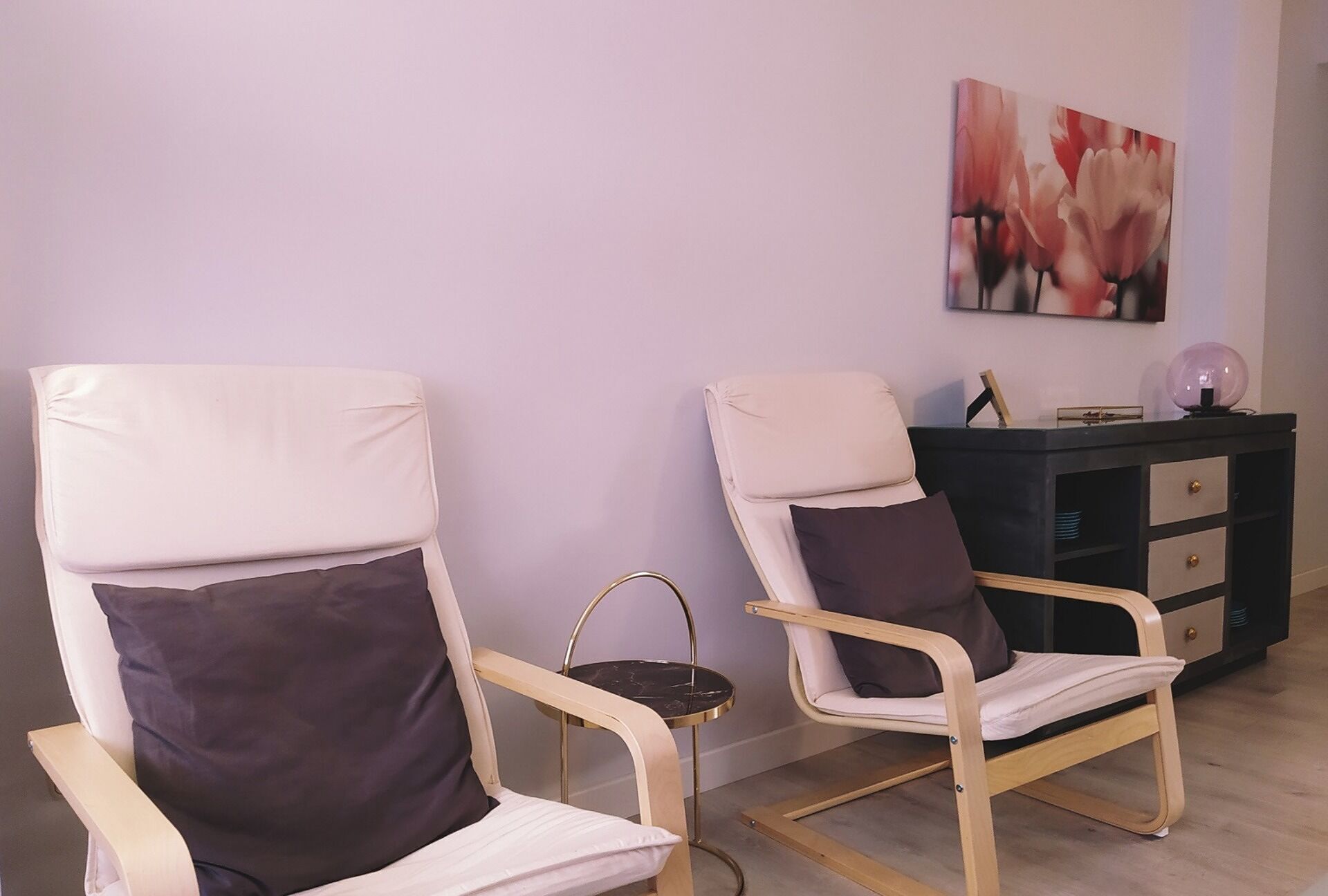 Deux chaises avec des coussins, une petite table et un meuble noir avec des tiroirs.