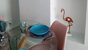 Un comedor con mesa de vidrio, sillas rosadas y una decoración de flamenco rosa.