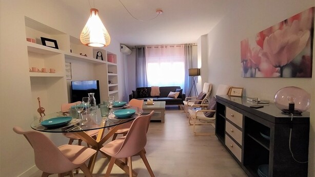 Una sala de estar moderna con un sofá, una mesa de comedor con sillas, un televisor y una chimenea.