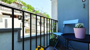 Un balcon avec une chaise, une petite table et des plantes en pot.