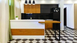 Une cuisine moderne avec un îlot central, des meubles de couleur noire et un carrelage à motifs géométriques.