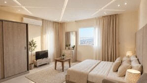 Un dormitorio moderno con cama, sofá, televisor y vistas a la ciudad.