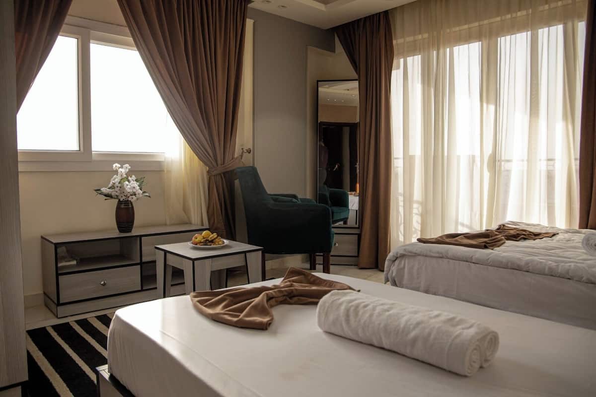 A hotel room with a bed, a chair, a small table, and a mirror.
