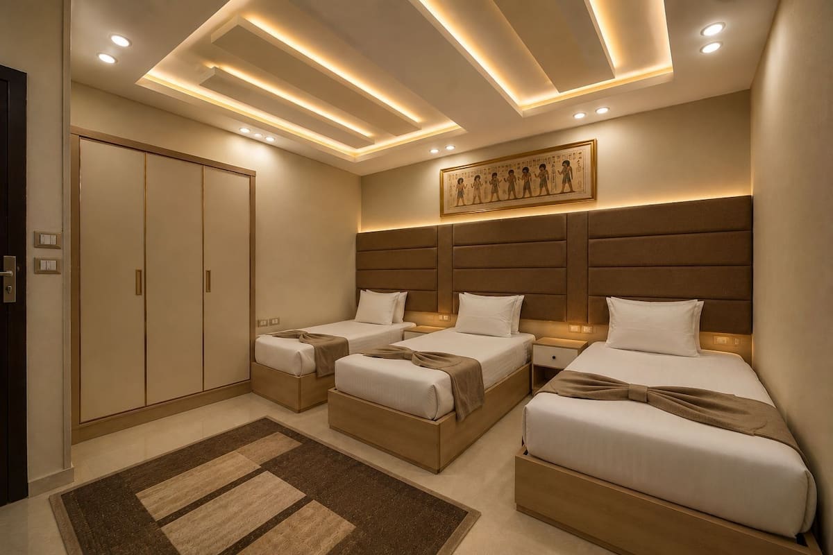 A hotel room with three beds, a large wall mural, recessed ceiling lighting, and a carpeted floor.
