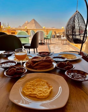 Una mesa con comida y bebidas, una lámpara colgante y vistas a pirámides.