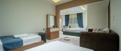 Une chambre d’hôtel moderne avec deux lits, un canapé, une commode et un grand miroir.
