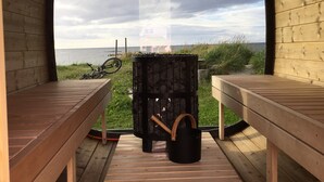 A wooden bench area with a view of the beach and a house in the distance. - Midnattsol rom og hytter (Andoy)