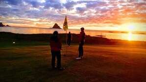 A sunset view from a golf course with two people standing on the grass. - Midnattsol rom og hytter (Andoy)