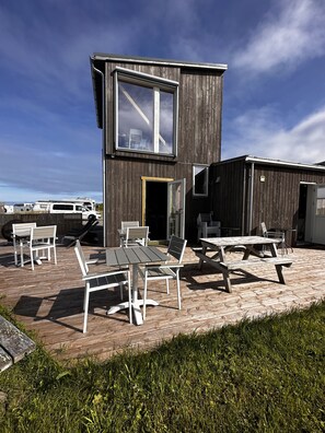 A modern building with a large window and a deck with outdoor furniture.