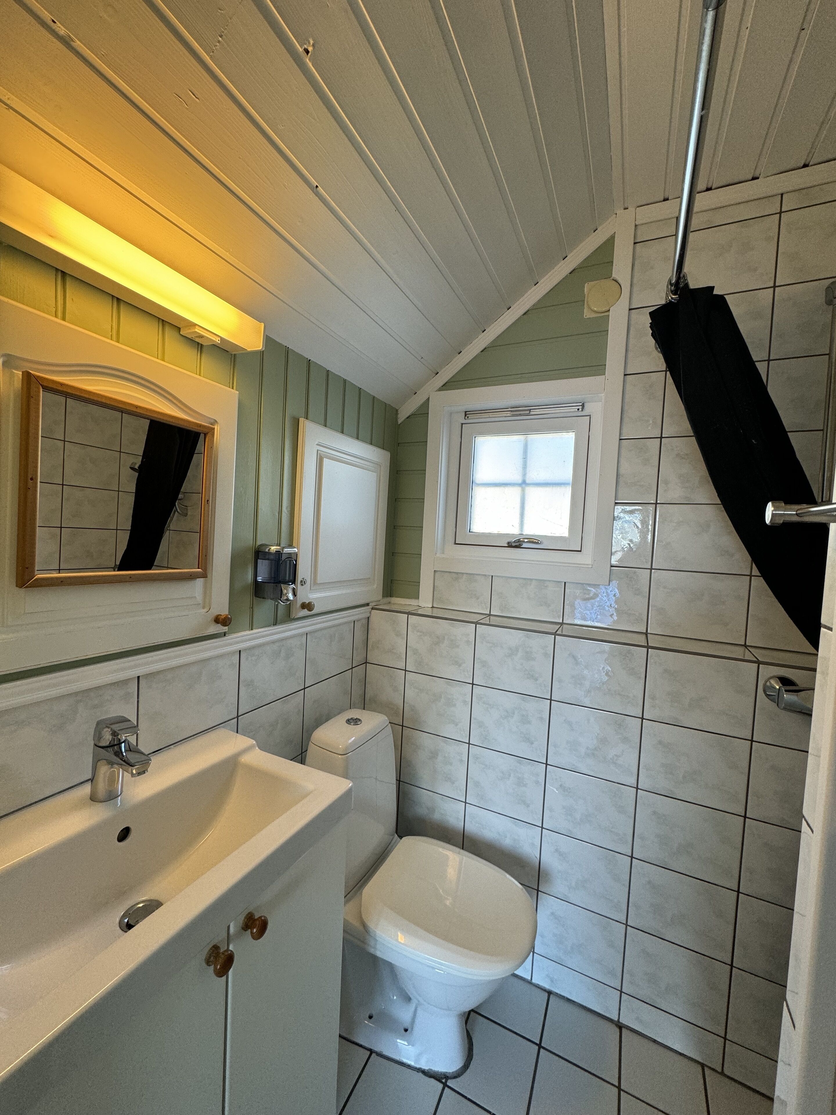 Un baño con un lavamanos blanco, un inodoro y una ventana.
