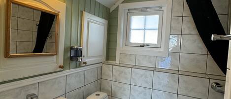 Un baño con un lavamanos blanco, un inodoro y una ventana.