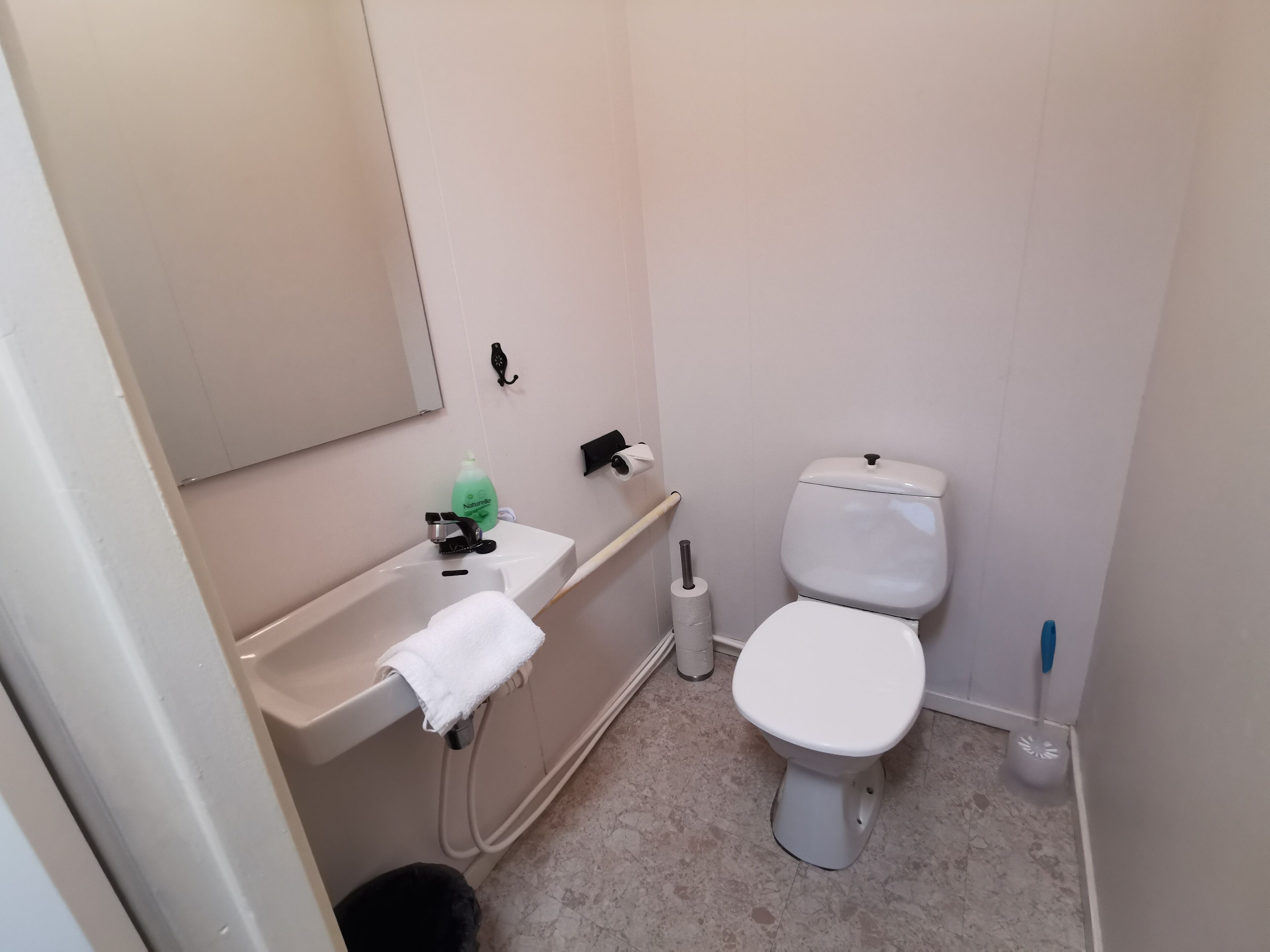 Un baño pequeño y limpio con inodoro, lavamanos y espejo.