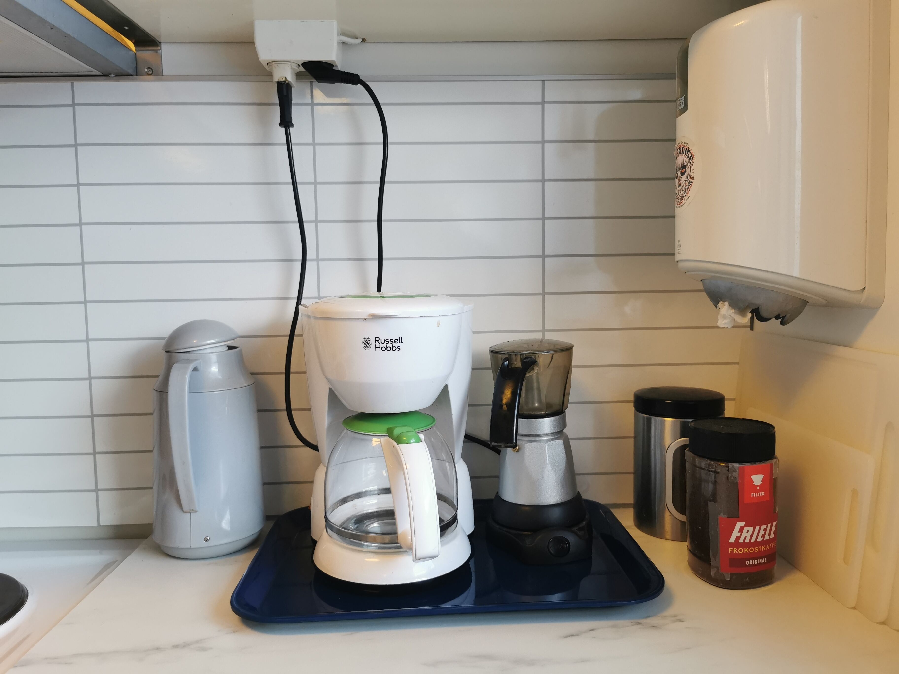 Una cucina con una macchina da caffè, un bollitore e un macinino per il caffè sul piano di lavoro.