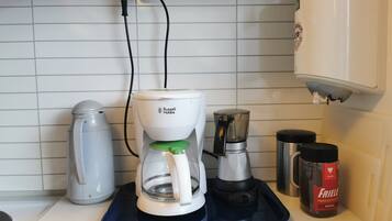 Una cucina con una macchina da caffè, un bollitore e un macinino per il caffè sul piano di lavoro.
