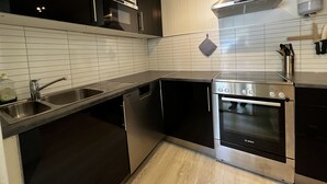 A modern kitchen with stainless steel appliances, a dishwasher, and a microwave. - Midnattsol rom og hytter (Andoy)