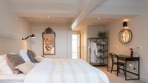 Une chambre à coucher comprenant un lit, une lampe de chevet, un miroir, une armoire, un bureau et une chaise.