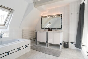 Un baño moderno con tragaluz, un espejo grande, una bañera y una zona de ducha.
